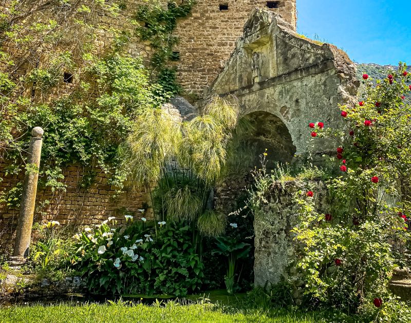 Giardino di Ninfa scorcio del castello con acqua calle e rose