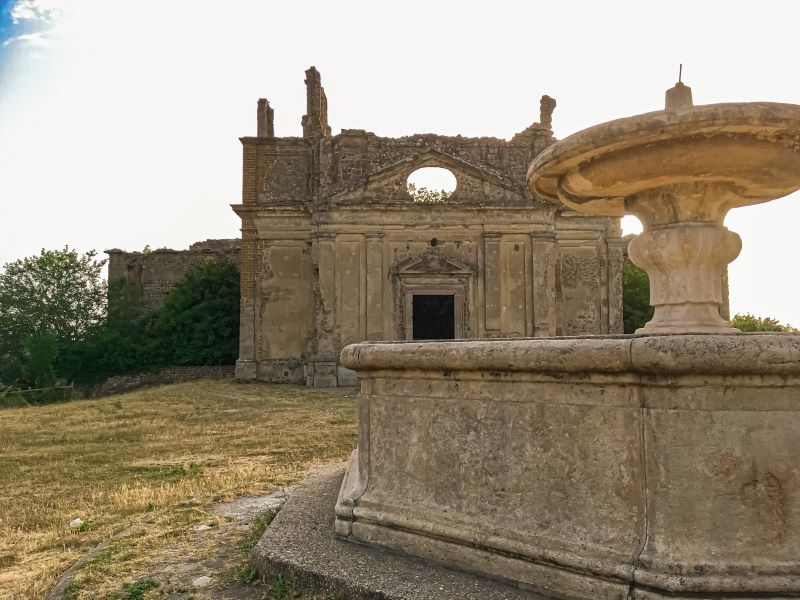 Antica Monterano la fontana ottagonale nel borgo fantasma e la chiesa di San Bonaventura sullo sfondo